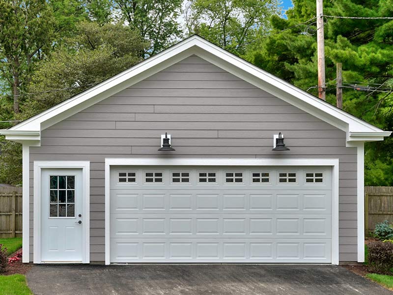 Gray detached garage with a white door, large white garage door, and two black outdoor lights above.